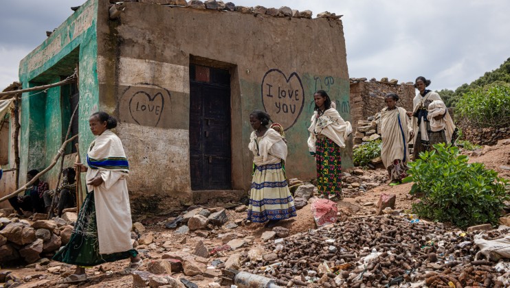 Women walking past a pile of UXO in Navi village, Tigray region